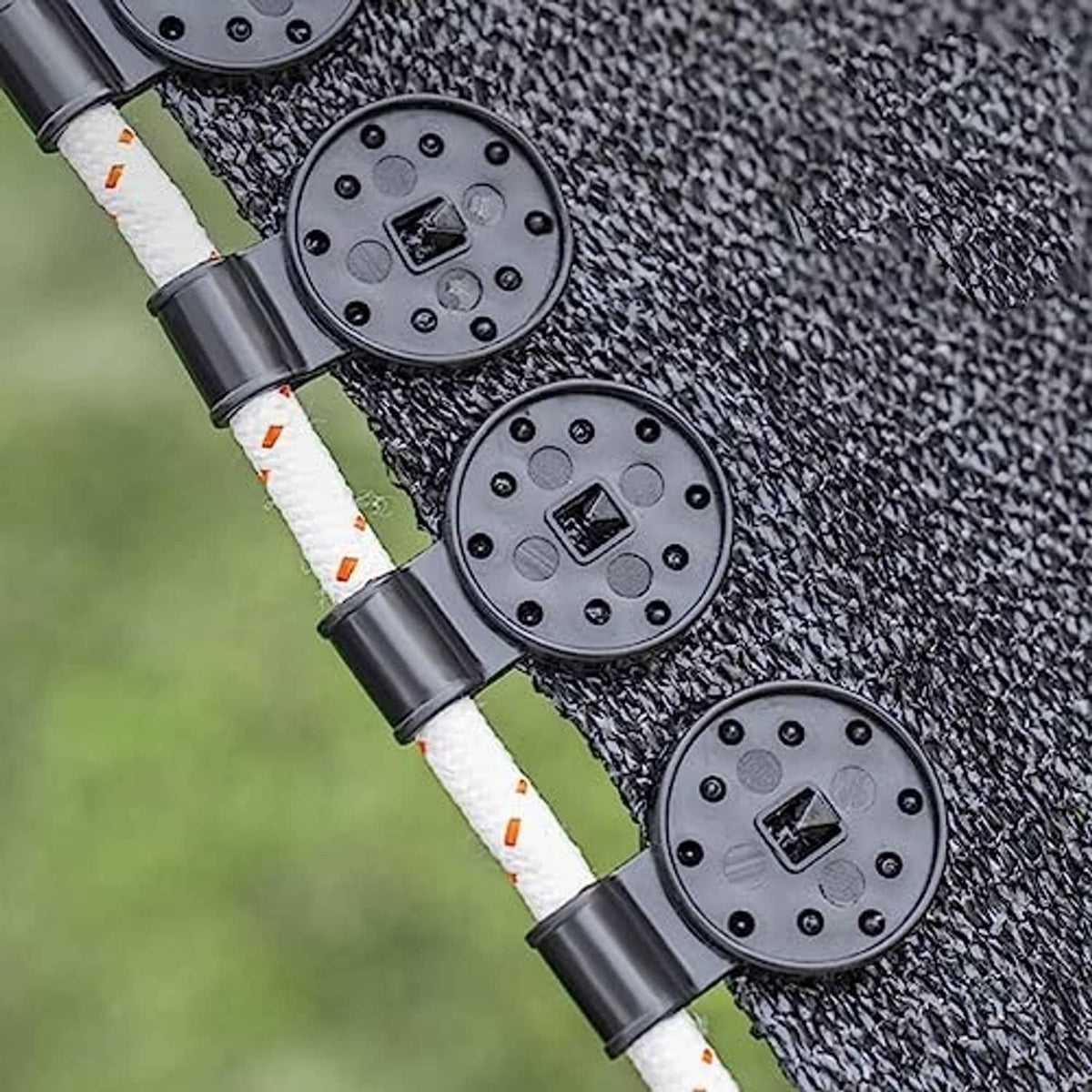 Black round plastic net clips locking onto shade cloth mesh along a rope