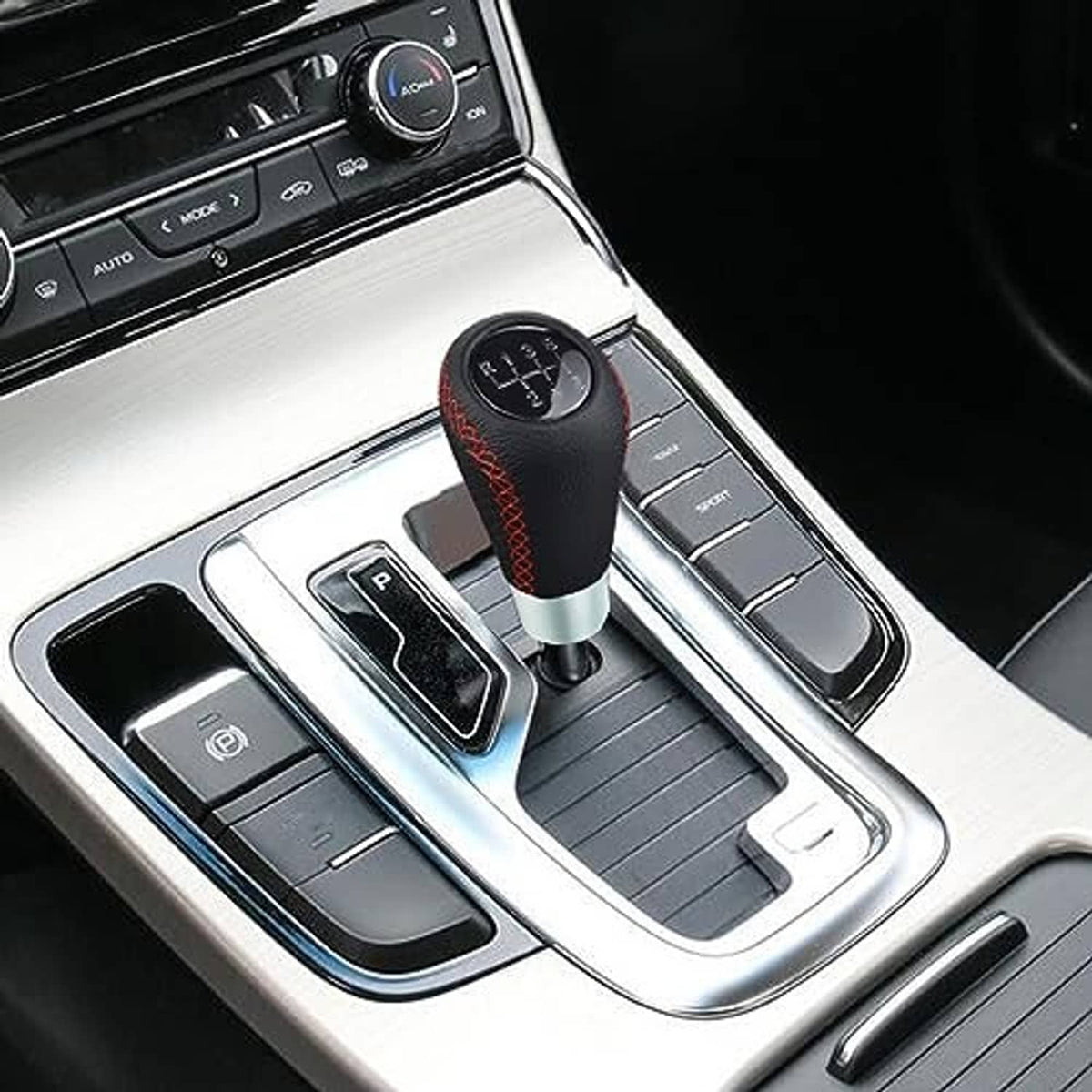 Leather shift knob in car console, black with red stitching and 6-speed shift dial