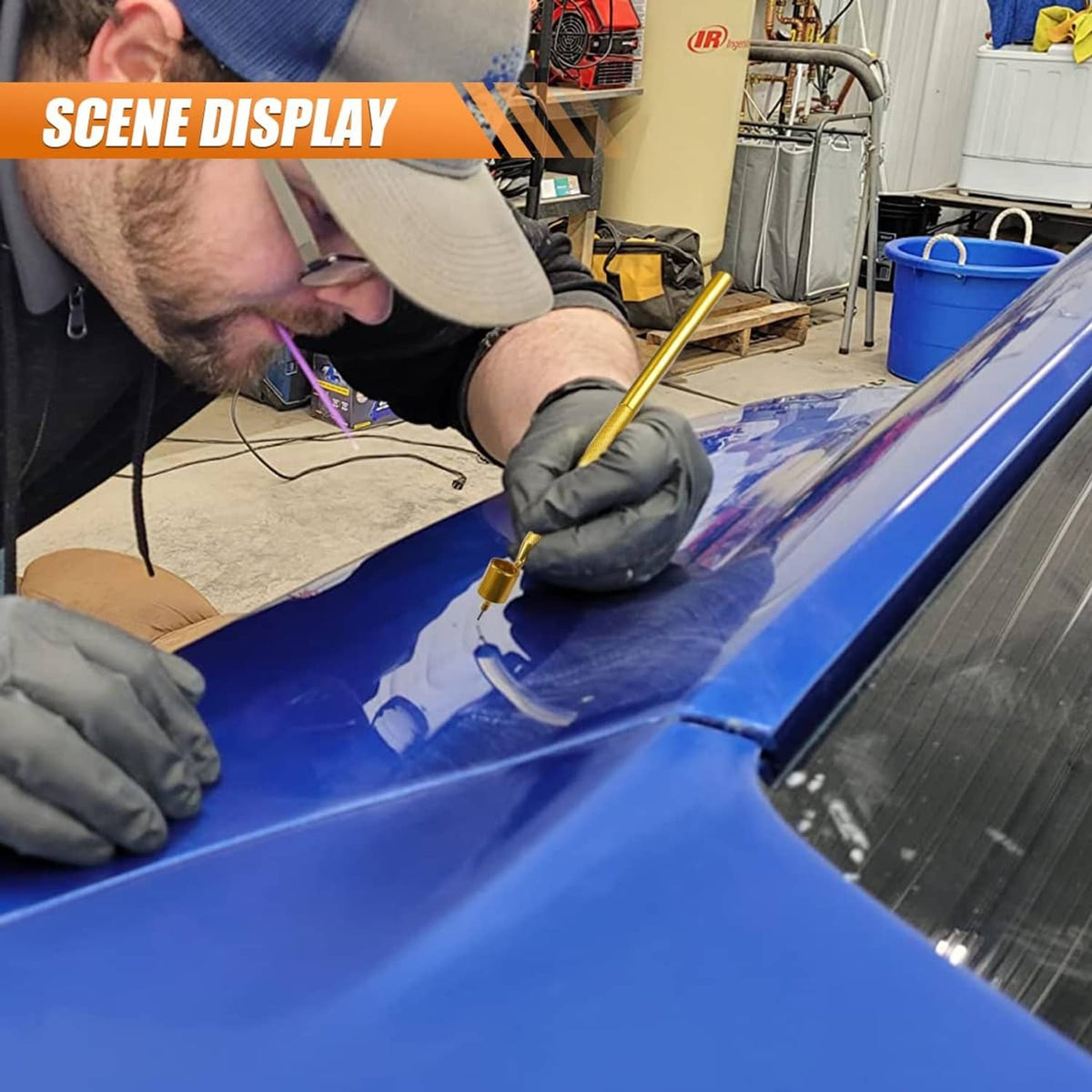 Gold paint pen touching up a blue car panel in a workshop