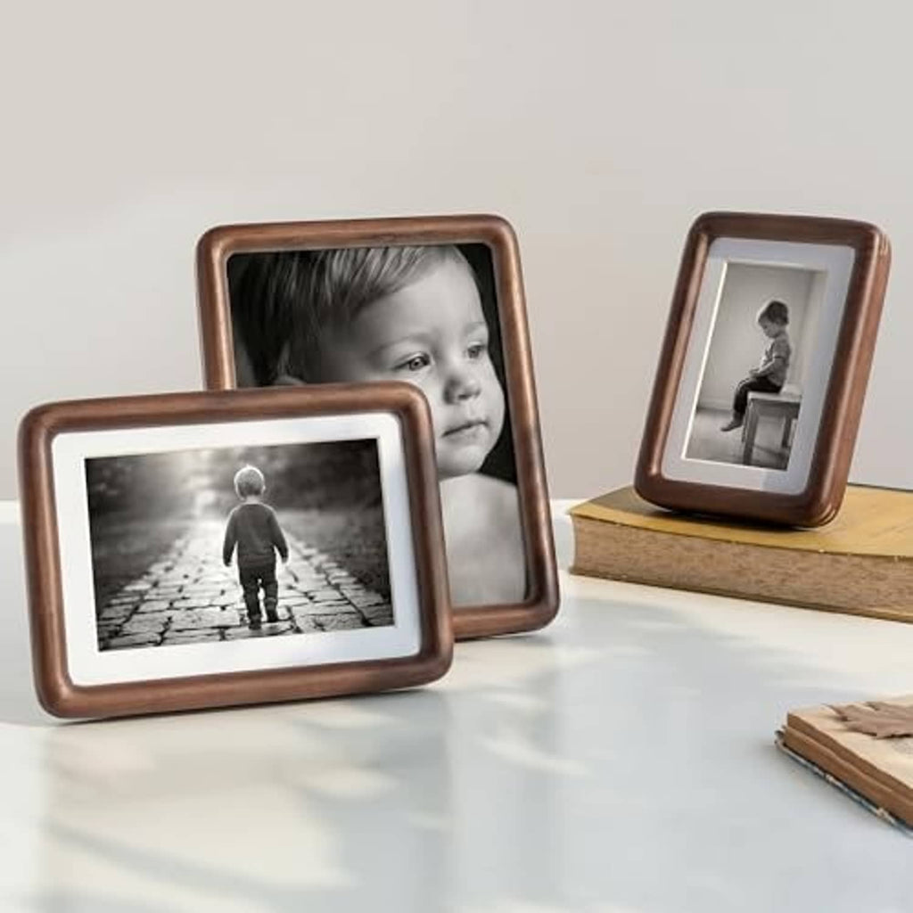 Three walnut picture frames with rounded corners, tabletop display of photos