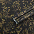 Black and gold botanical peel-and-stick wallpaper roll with scrolling leaf pattern