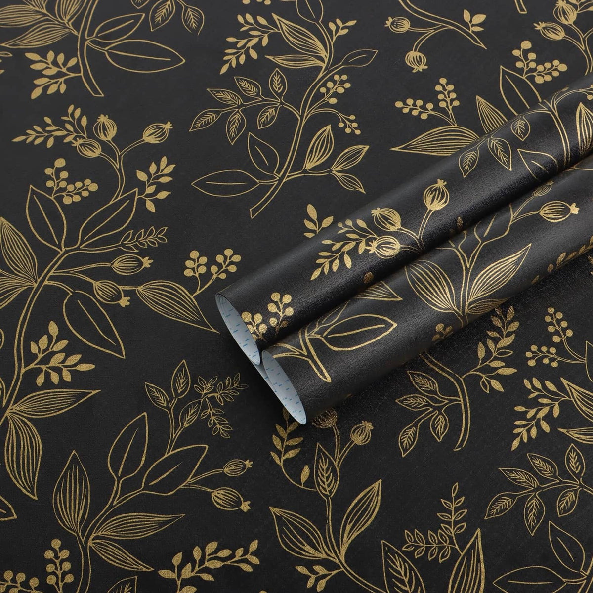 Black and gold botanical peel-and-stick wallpaper roll with scrolling leaf pattern