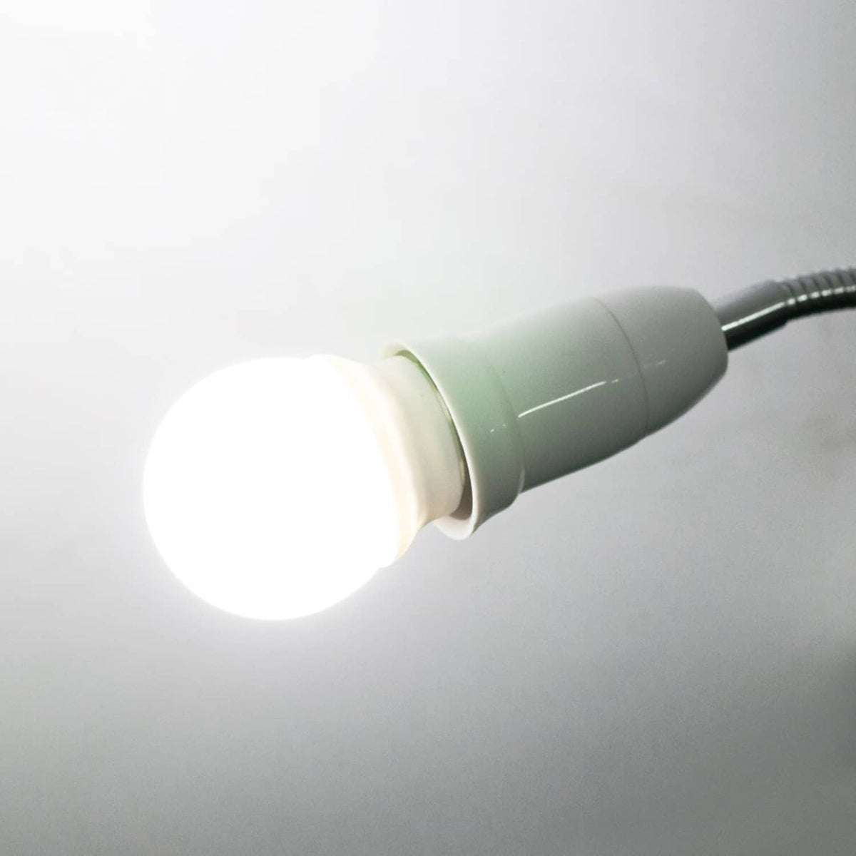 Flexible lamp extender with a lit bulb and white socket holder on the gooseneck
