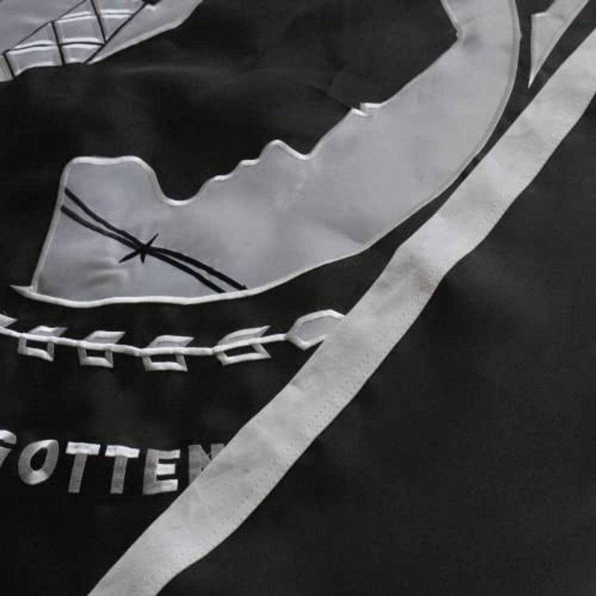 Close-up of POW*MIA flag embroidery with gray portrait silhouette and chain border