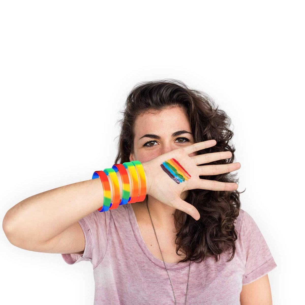 Rainbow pride wristbands stacked on a person’s wrist and forearm