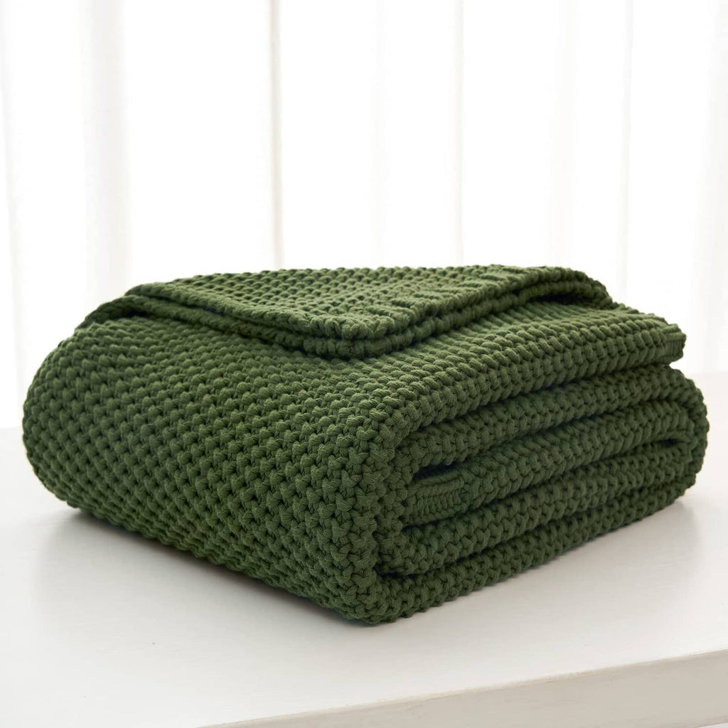 Olive green chunky cable knit throw blanket neatly folded on a surface