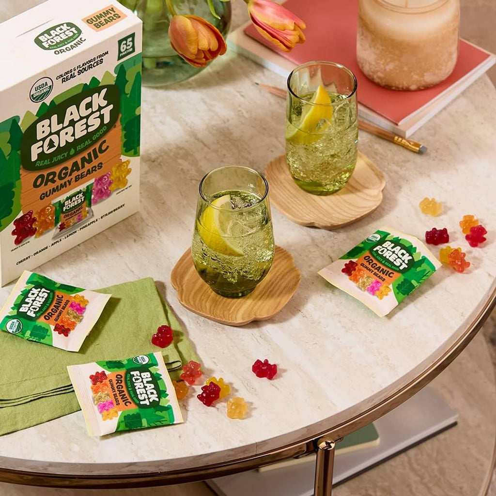 Organic gummy bear pouch with scattered gummies and small flavor packets on a table.