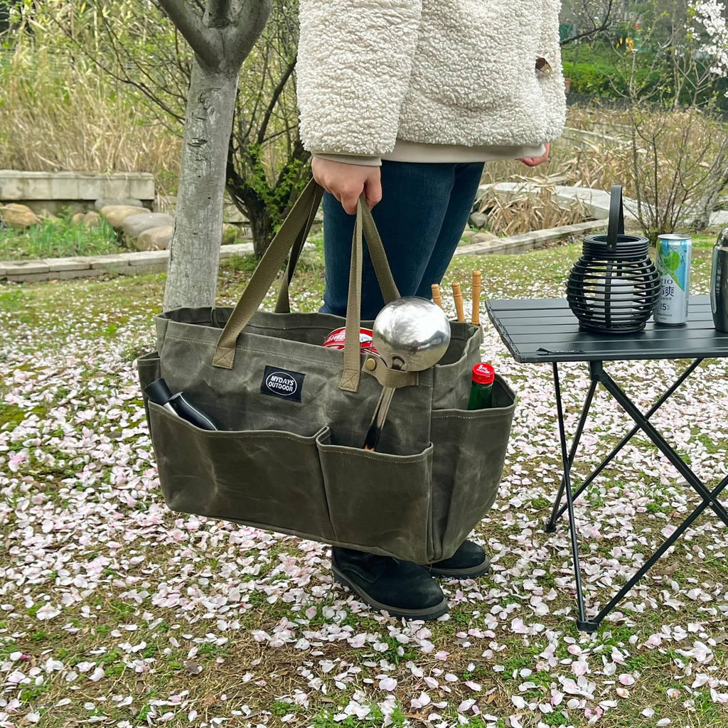 Army green portable tool storage tote carried outdoors with open organizer compartments