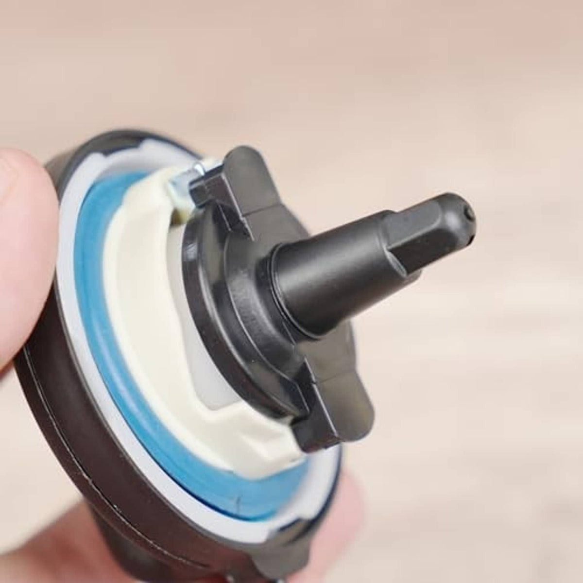 Fuel tank filler cap with blue gasket ring, black insert, and tethered handle