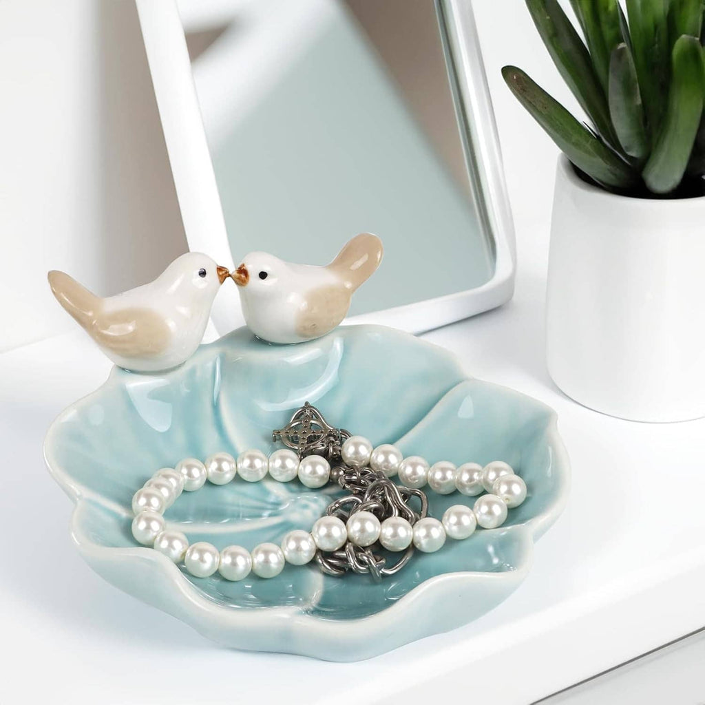 Ceramic lotus leaf jewelry tray with two white bird ring holders holding pearl necklaces and charms