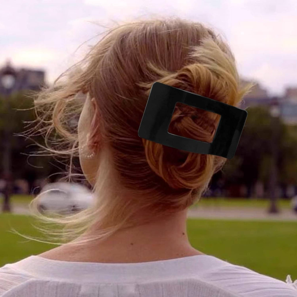 Bright black flat rectangular hair clip holding a messy bun at the back of hair