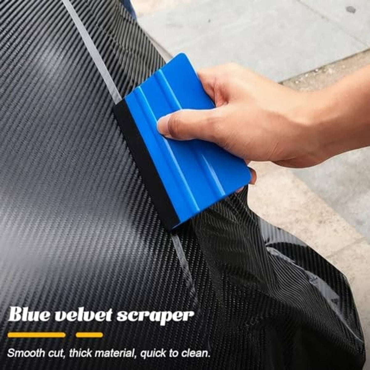 Blue vinyl wrap scraper tool held in hand for smoothing car film on a textured surface