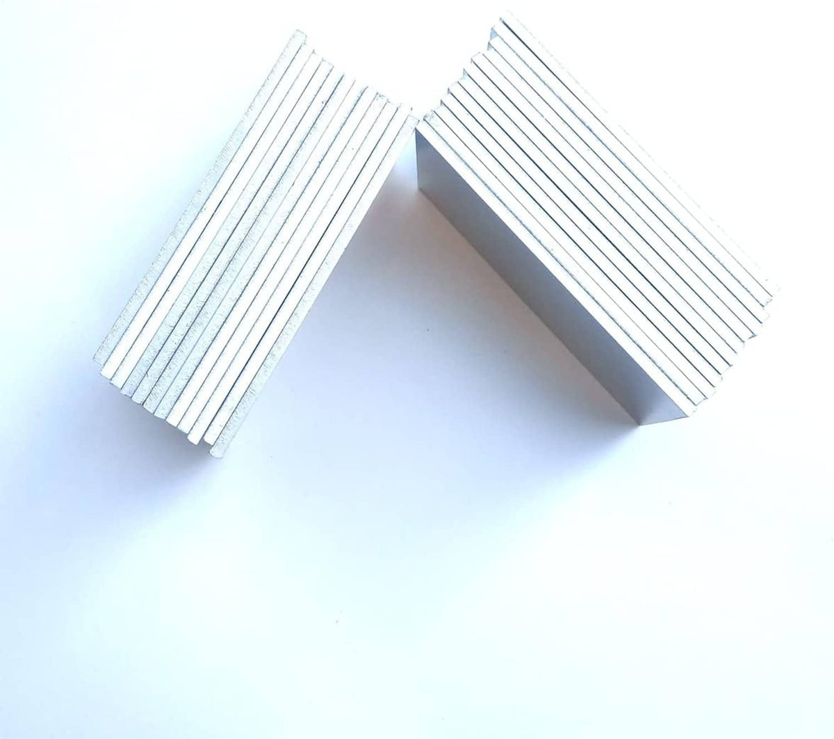 Two open stacks of silver aluminum coupon sheets, angled to show layered thickness.