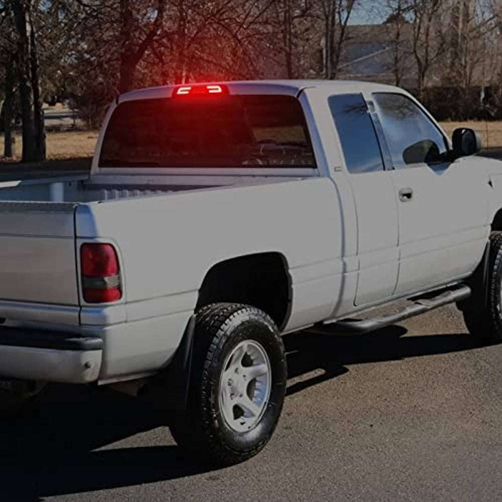 Smoked LED third brake light glowing red on white pickup truck rear