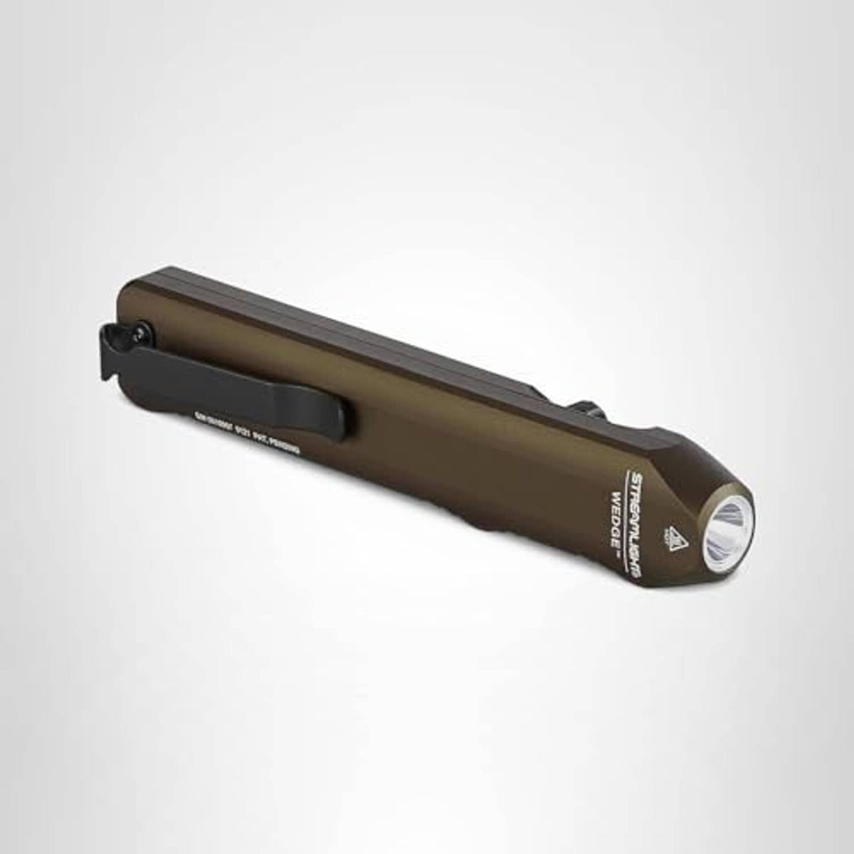 Coyote tan wedge flashlight on its side, with trigger and front lens visible