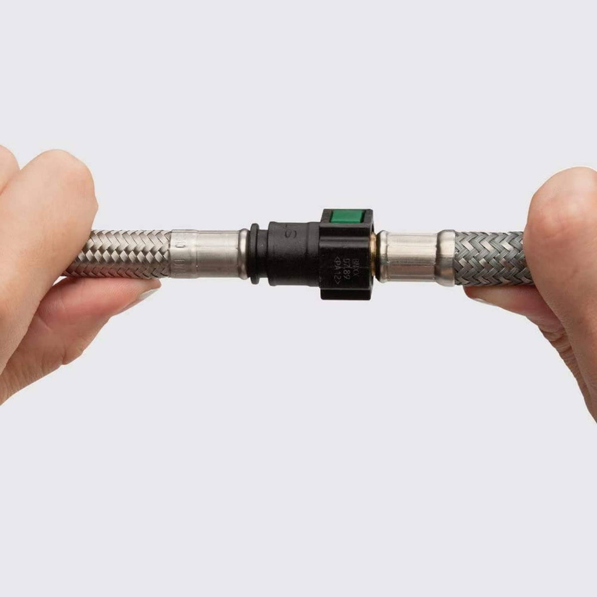 Braided faucet hose with black coupling and metal connector ends held by hands