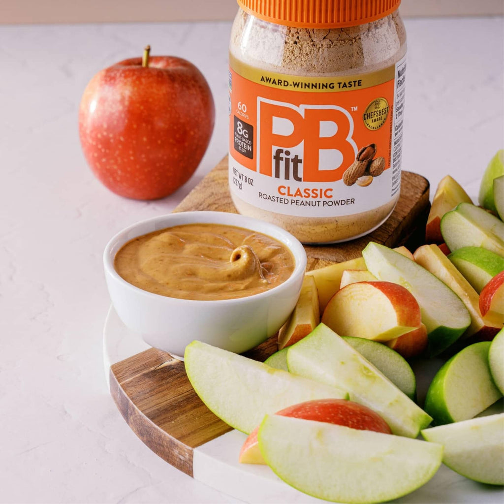 Peanut butter powder jar with bowl of peanut butter and sliced apples