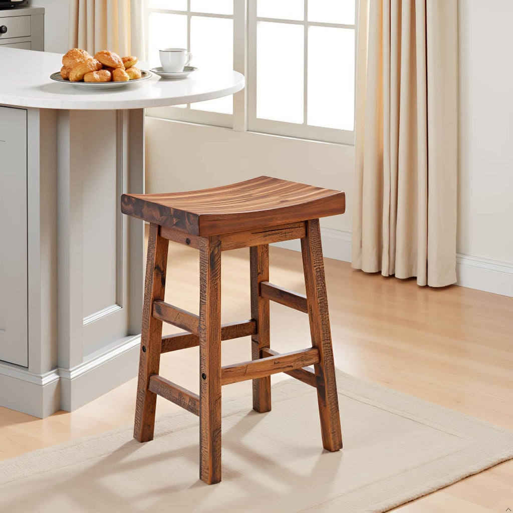 Natural wood counter-height bar stool with saddle seat beside a kitchen island