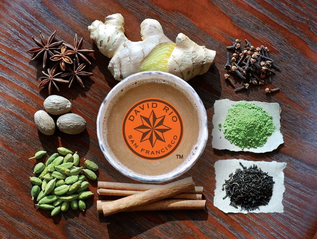 Chai spice mix in a cup with ginger root, star anise, cardamom, cinnamon, and green powder