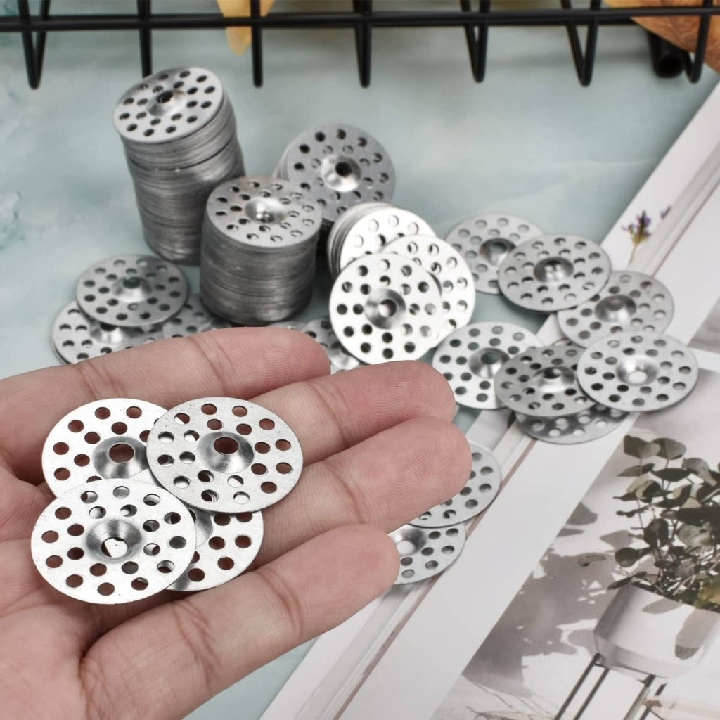 Hand holding several round metal plaster washers with center holes and small perimeter holes