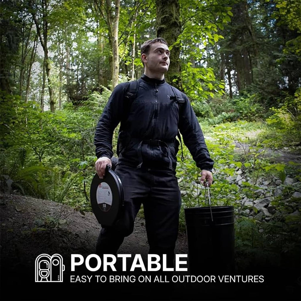 Black portable toilet lid held in hand outdoors, seat-side view