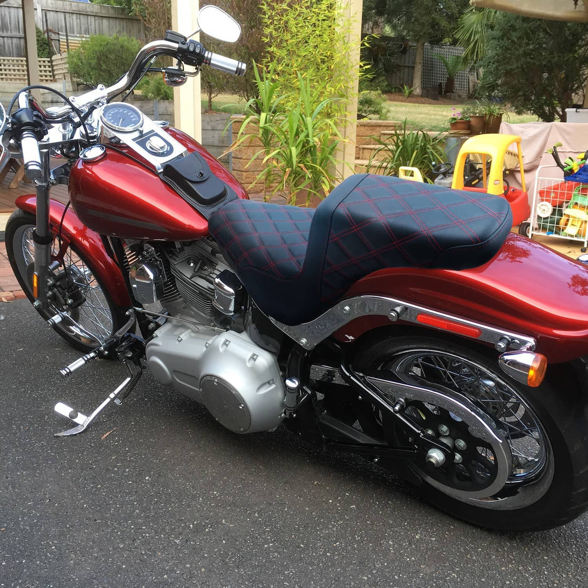 Motorcycle driver seat with black leather-look cover and red diamond stitching