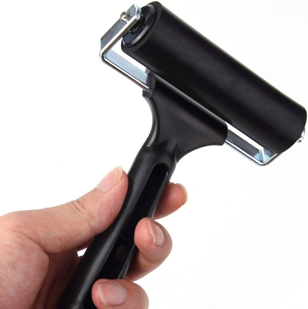 Rubber brayer roller held in hand, black handle and roller with metal bracket