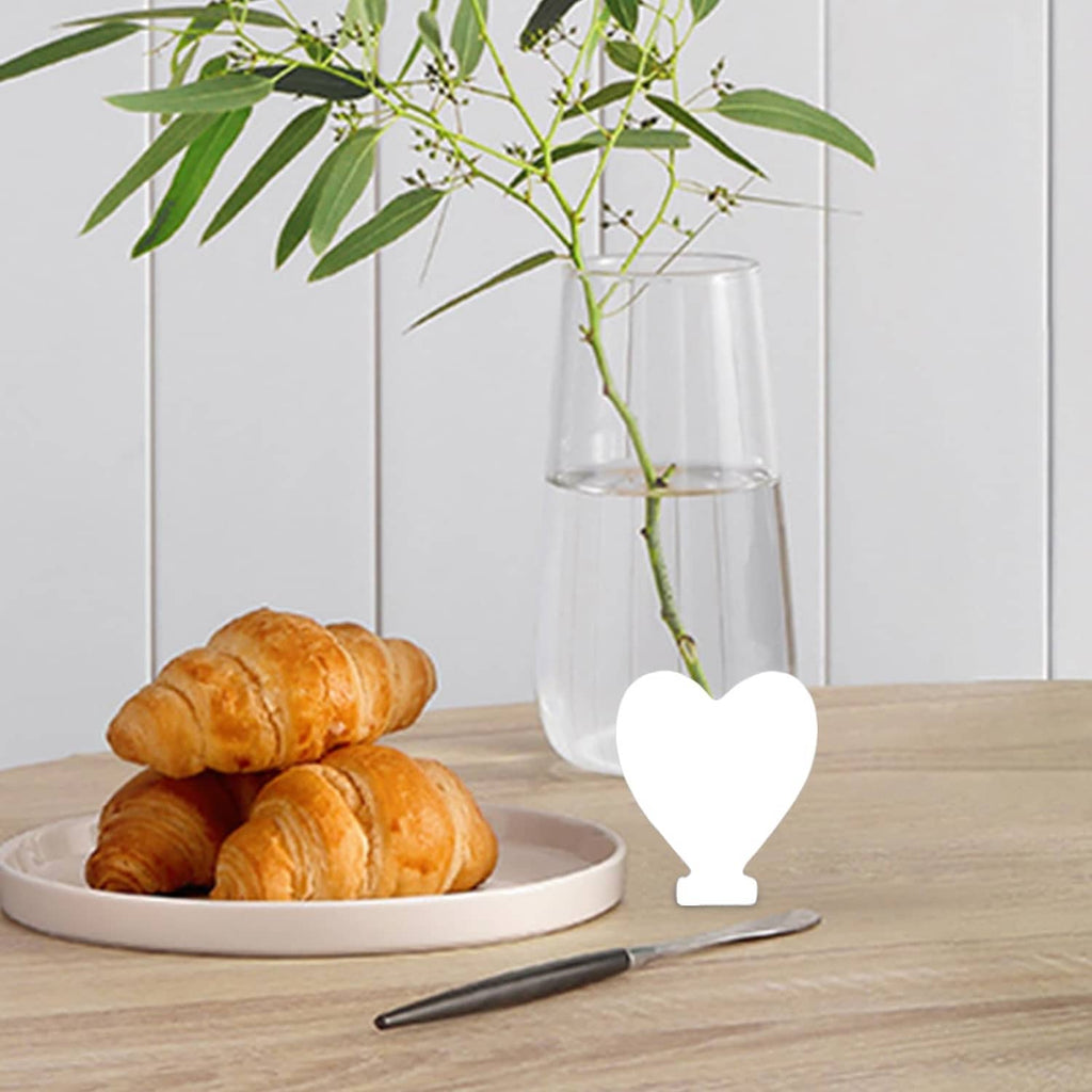 White wood heart-shaped cutout ornament placed on tabletop near plants and tray