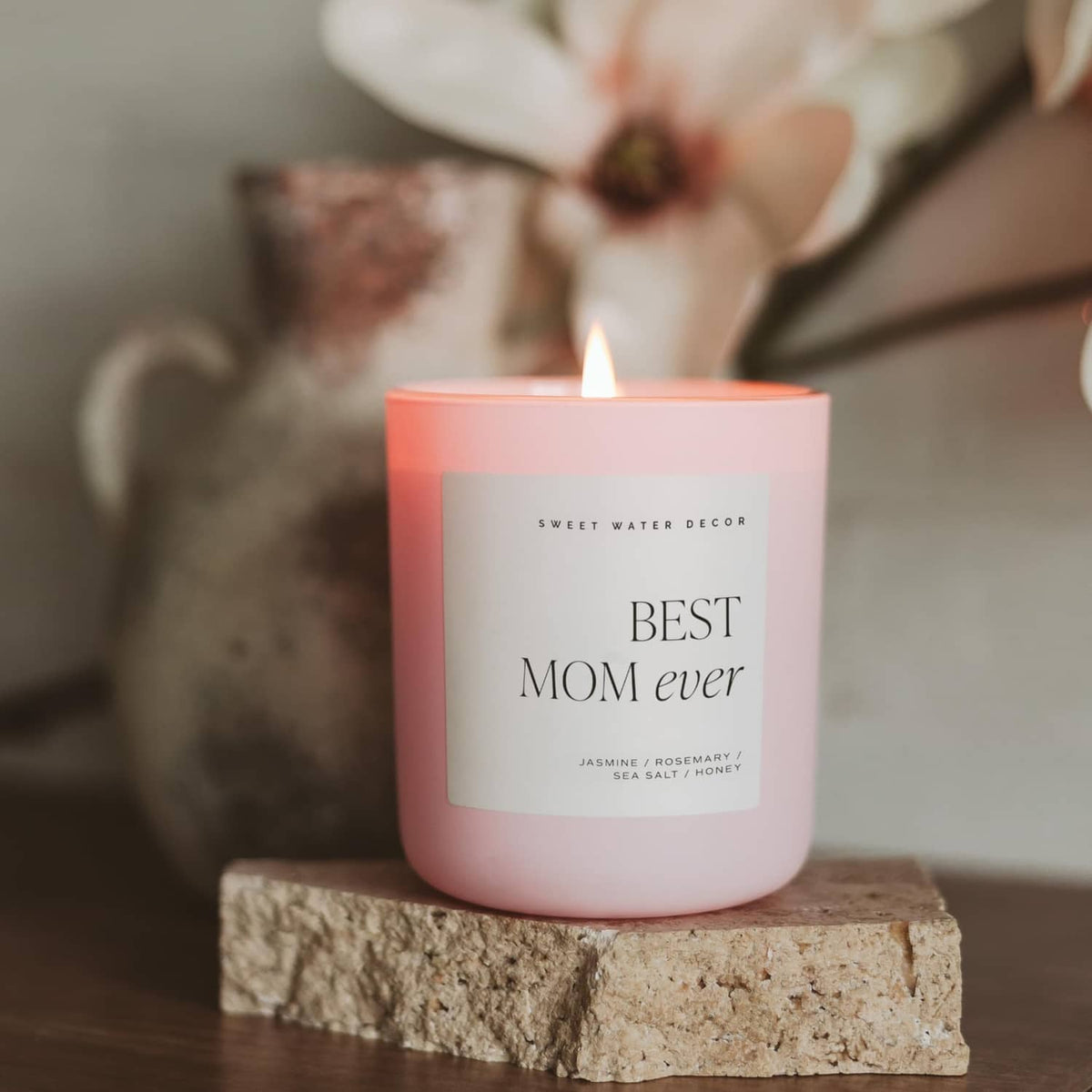 Pink-orange “Best Mom ever” scented candle jar with flame on stone block