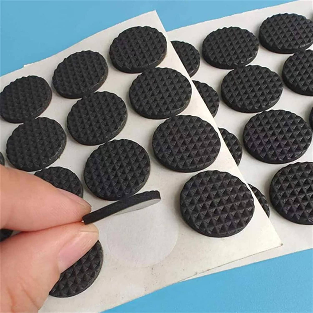 Round black felt furniture pads, textured pattern on backing sheets as shown by hand