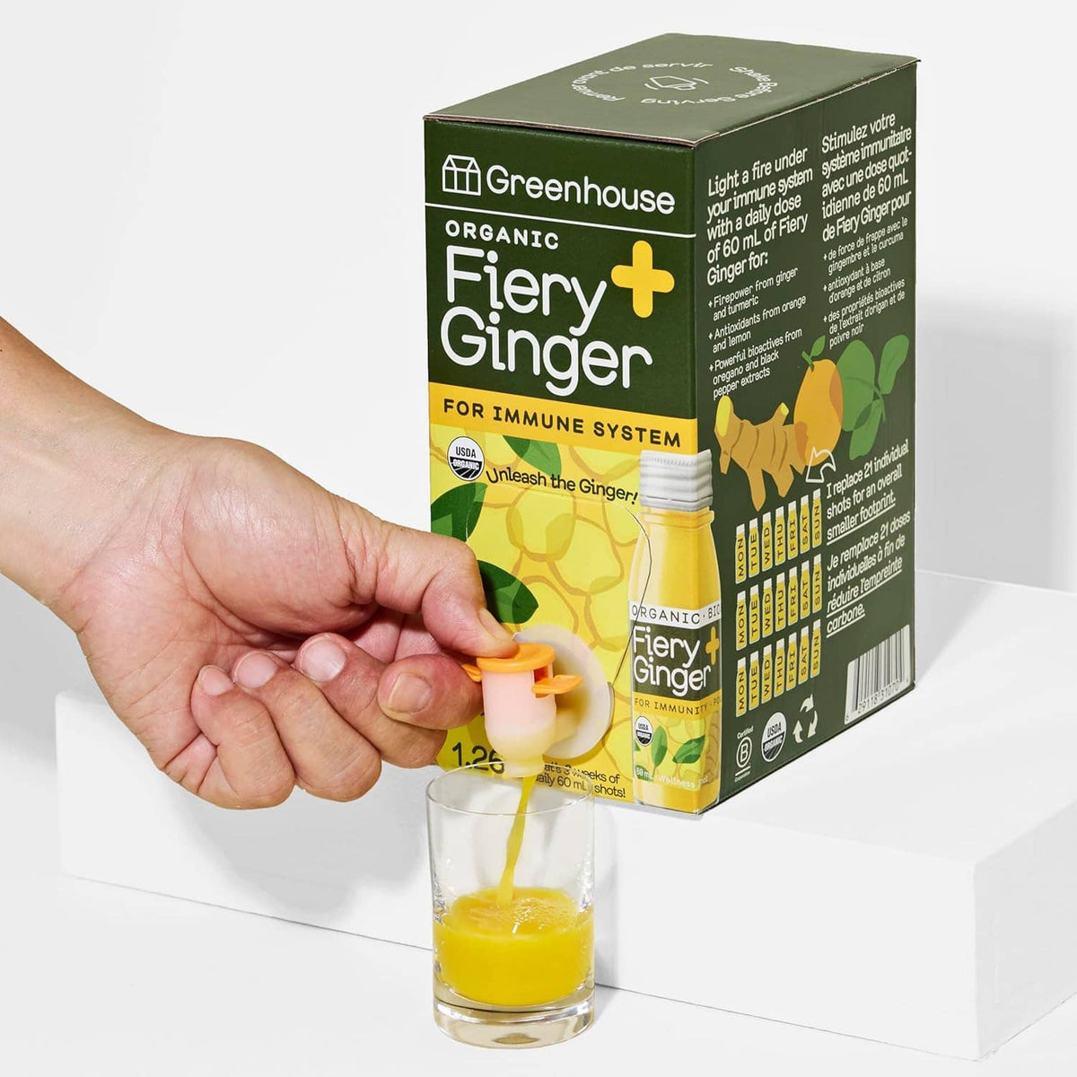 Organic cold-pressed fiery ginger immunity shot box with shot glass and hand dispensing