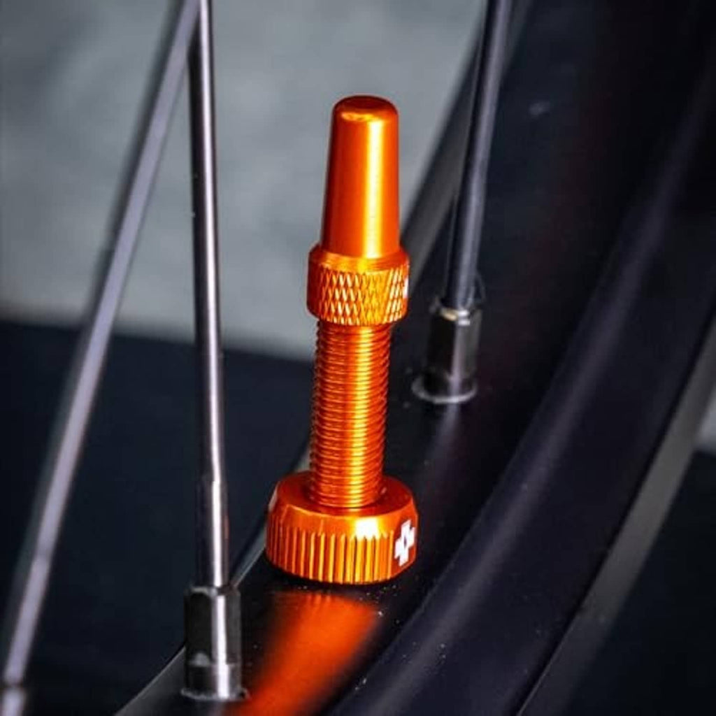 Single orange Presta tubeless valve stem with knurled grip and removable cap.