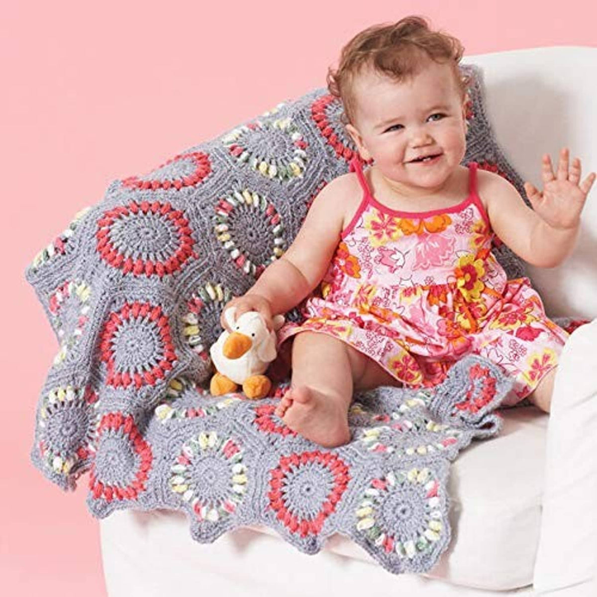 Crocheted baby blanket with gray hearts and multicolor circular motifs