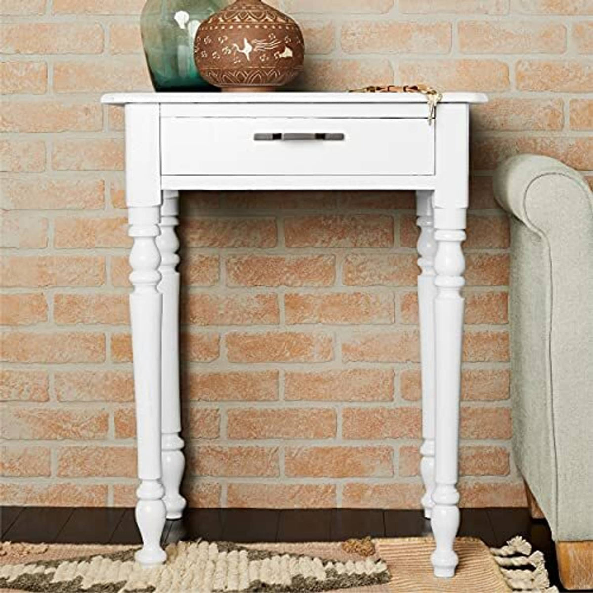 White side table with turned legs and drawer, styled against a brick wall