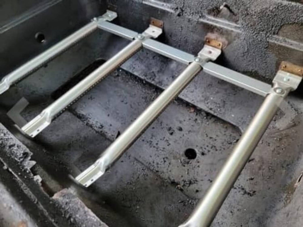 Installed gas grill burner frame with heat plates and metal burner tubes inside