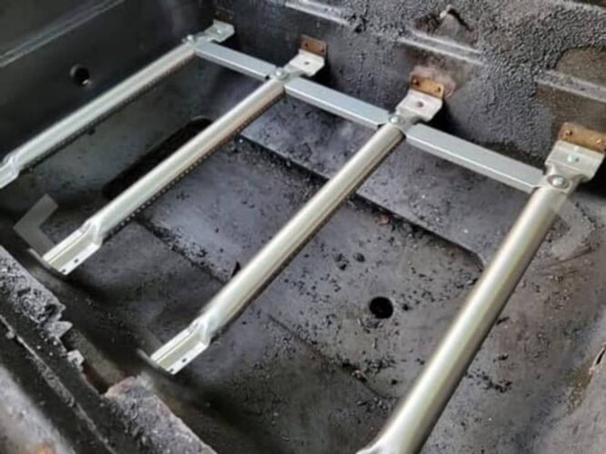 Installed gas grill burner frame with heat plates and metal burner tubes inside