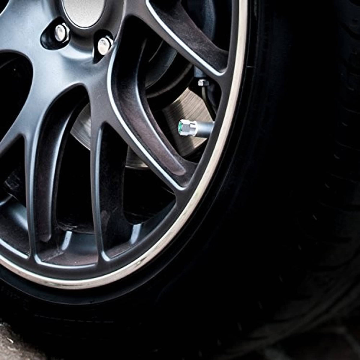Tire valve stem with installed silver metal cap and green N2 insert on wheel