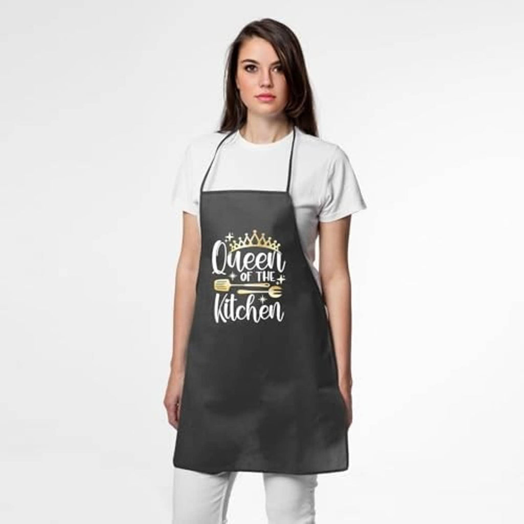 Black apron worn over a white shirt; "Queen of the Kitchen" front print