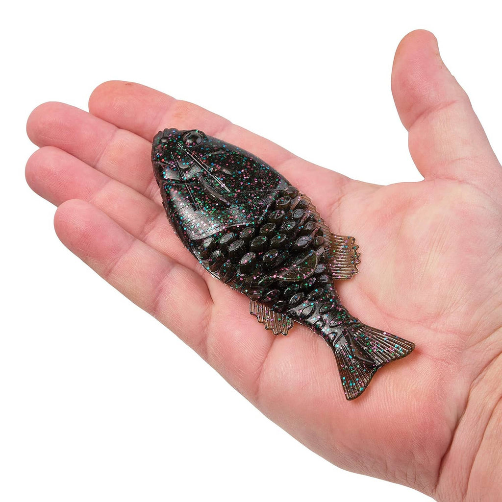 Soft plastic fishing bait in hand, dark glitter body with gill texture and tail