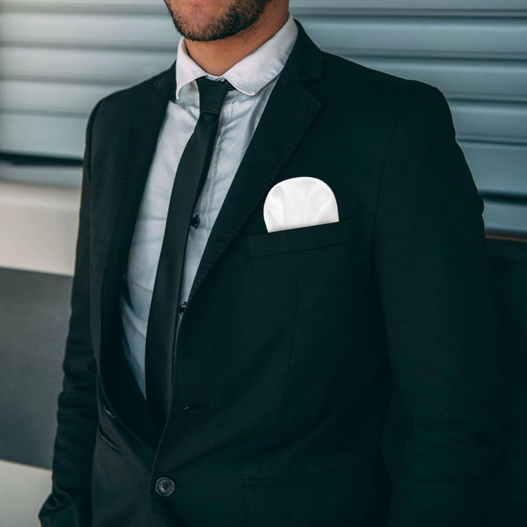 White pre-folded pocket square neatly placed in a dark suit breast pocket