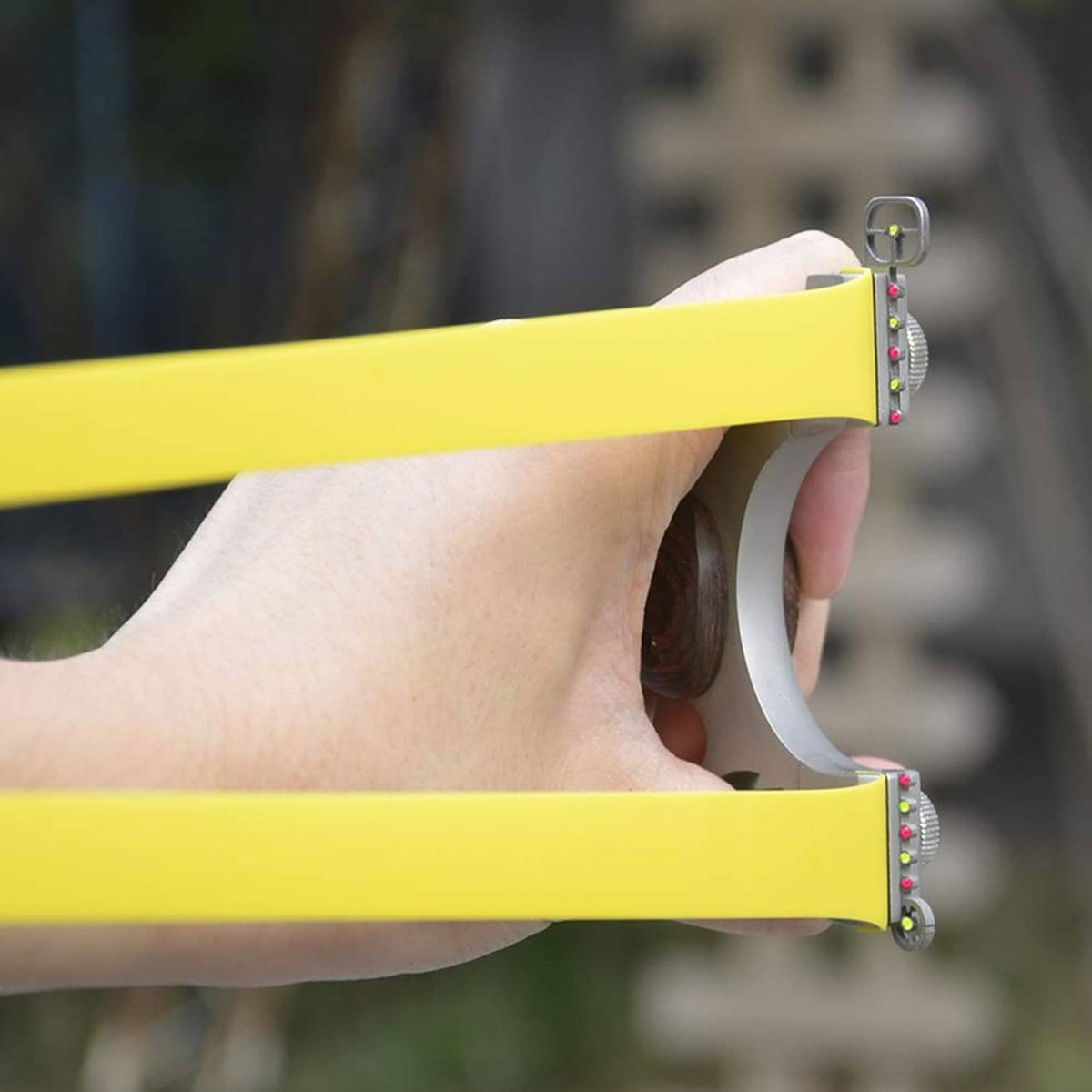 Hand holding yellow flat slingshot rubber bands attached to a slingshot