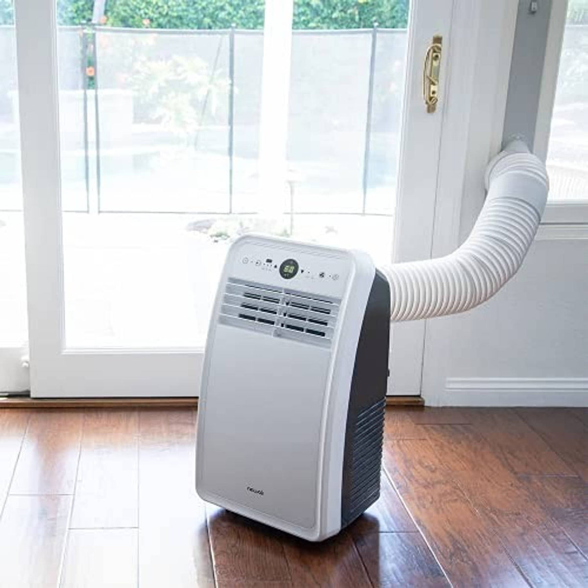Portable air conditioner with white exhaust hose routed to a window opening