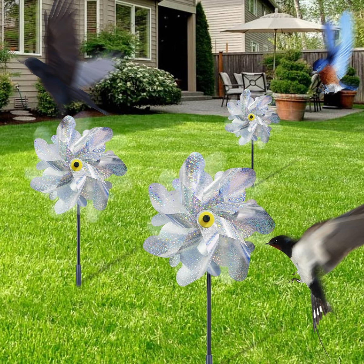 Silver reflective pinwheels on stakes with blue-silver blades in a yard setting
