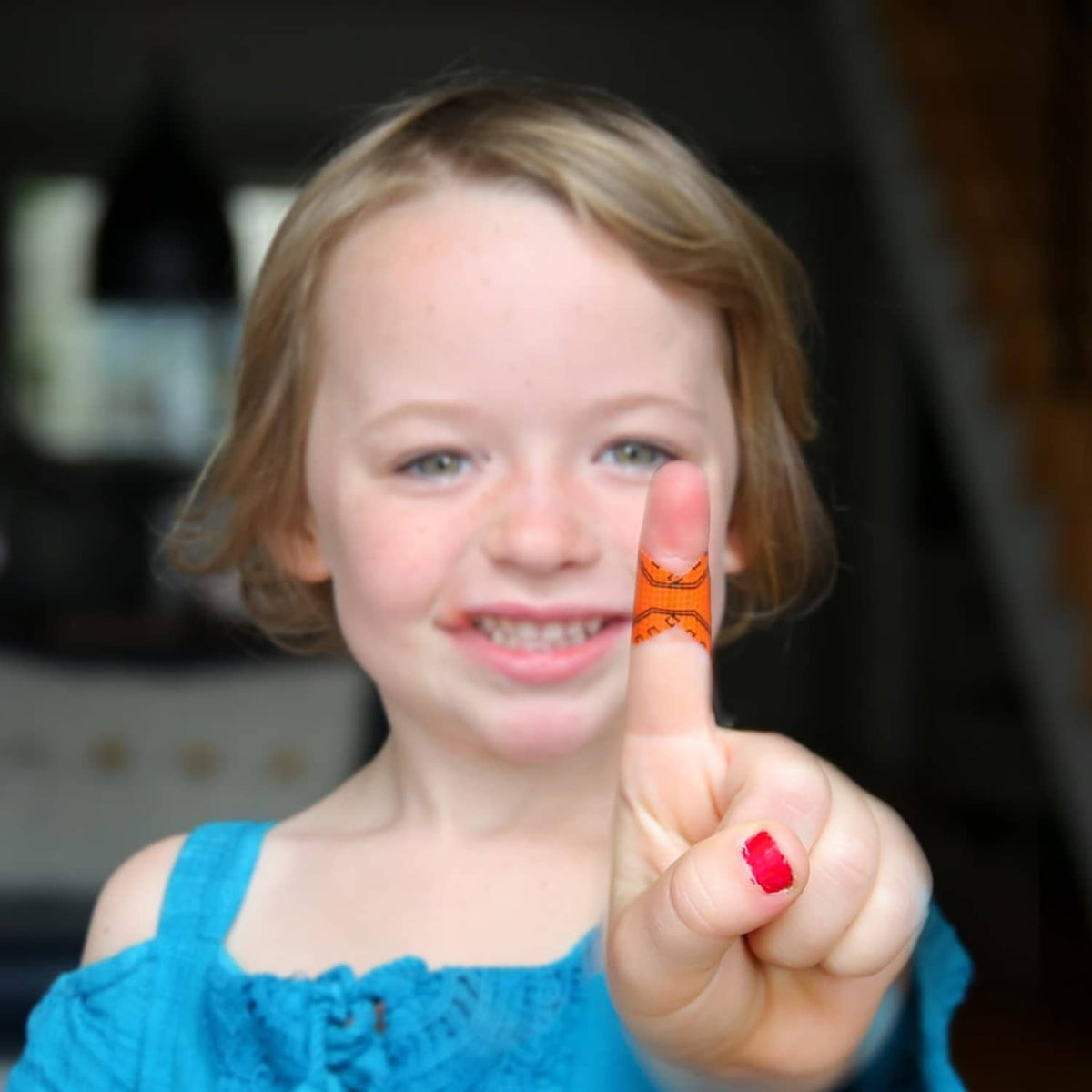 Orange fingertip bandage on finger held up for first aid tape use