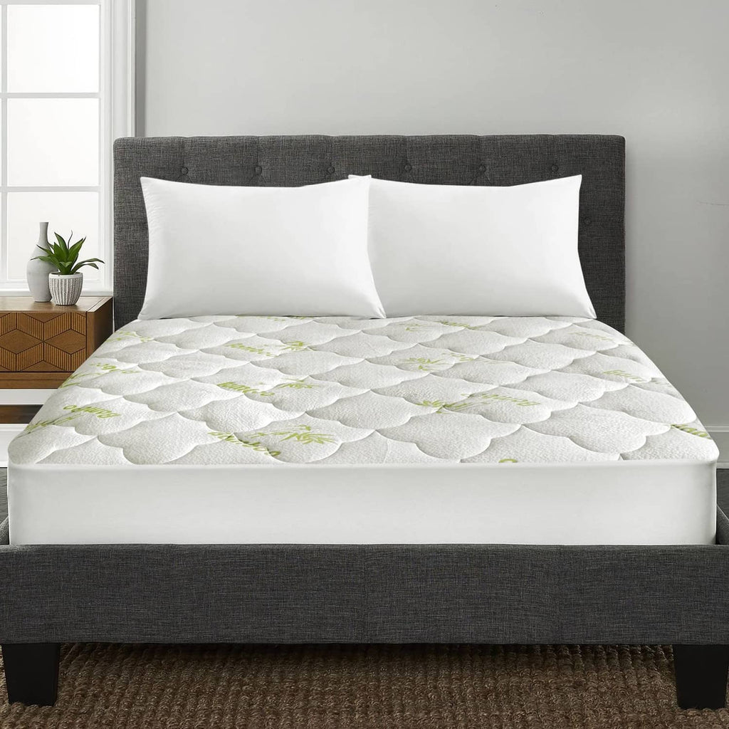 White quilted mattress pad cover with green bamboo pattern, fitted on queen bed