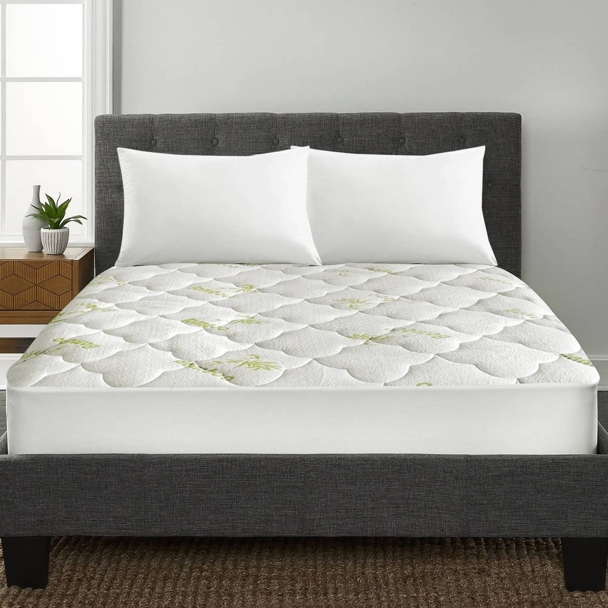 White quilted mattress pad cover with green bamboo pattern, fitted on queen bed