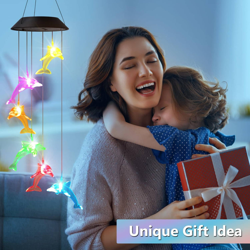 Mom holding a gift next to glowing multicolor solar dolphin wind spinner lights