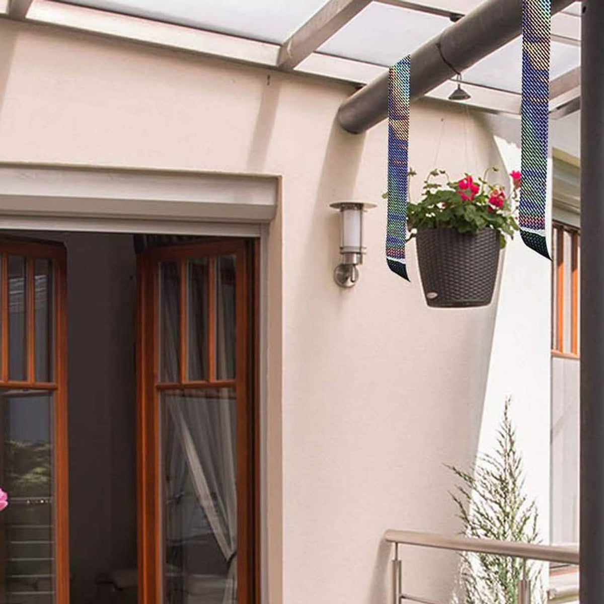 Holographic reflective tape strips tied across patio railing, rainbow metallic reflective finish