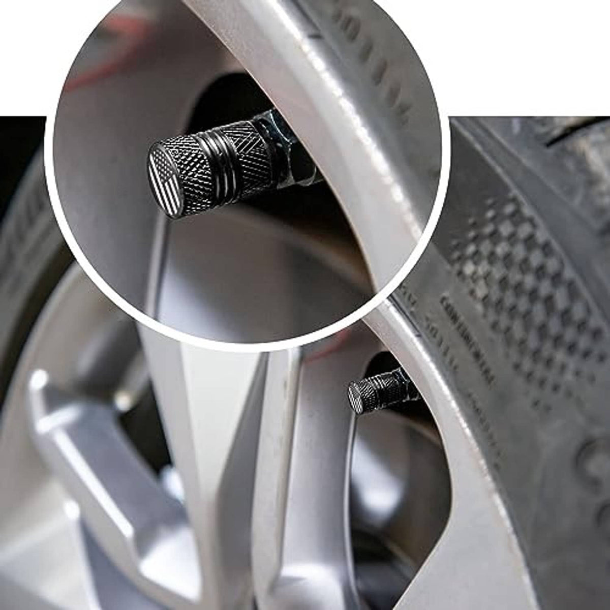 Black tire valve stem cap with paw-print badge installed on wheel rim valve
