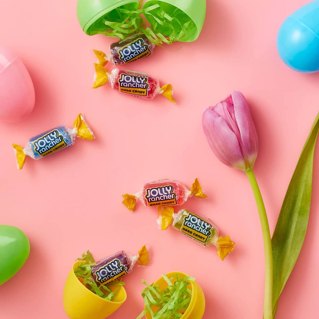 Assorted JOLLY RANCHER hard candy pieces scattered on pastel surface